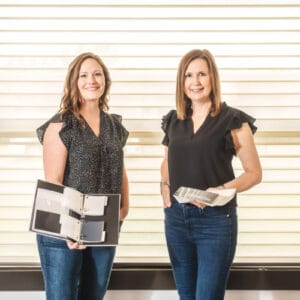 Two Women Standing Holding Samples