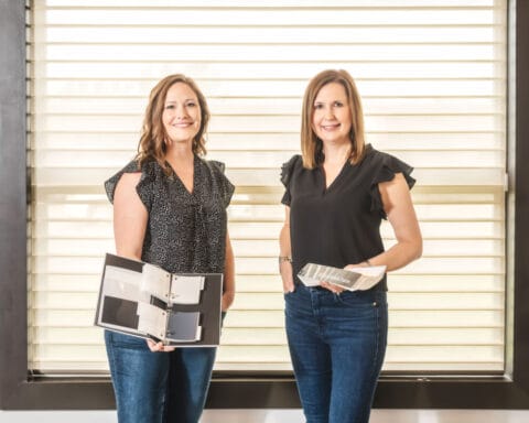 Two Women Standing Holding Samples